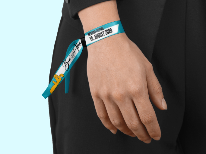 Hand mit einem bunten Festivalband, welches ein Hochzeitsdatum und die Namen des Brautpaars zeigt.
